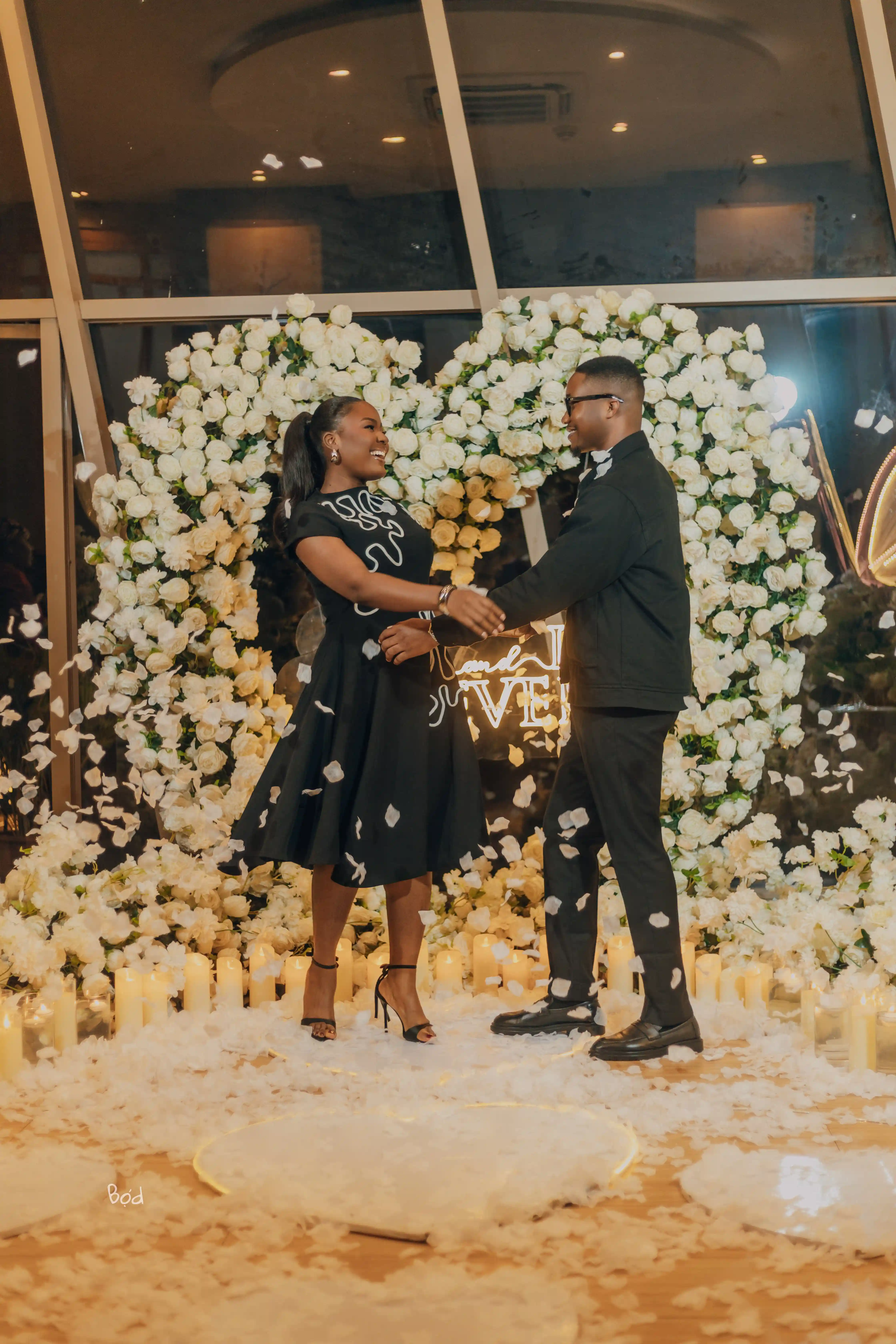 Priscilla and Kelvin holding hands amid falling petals